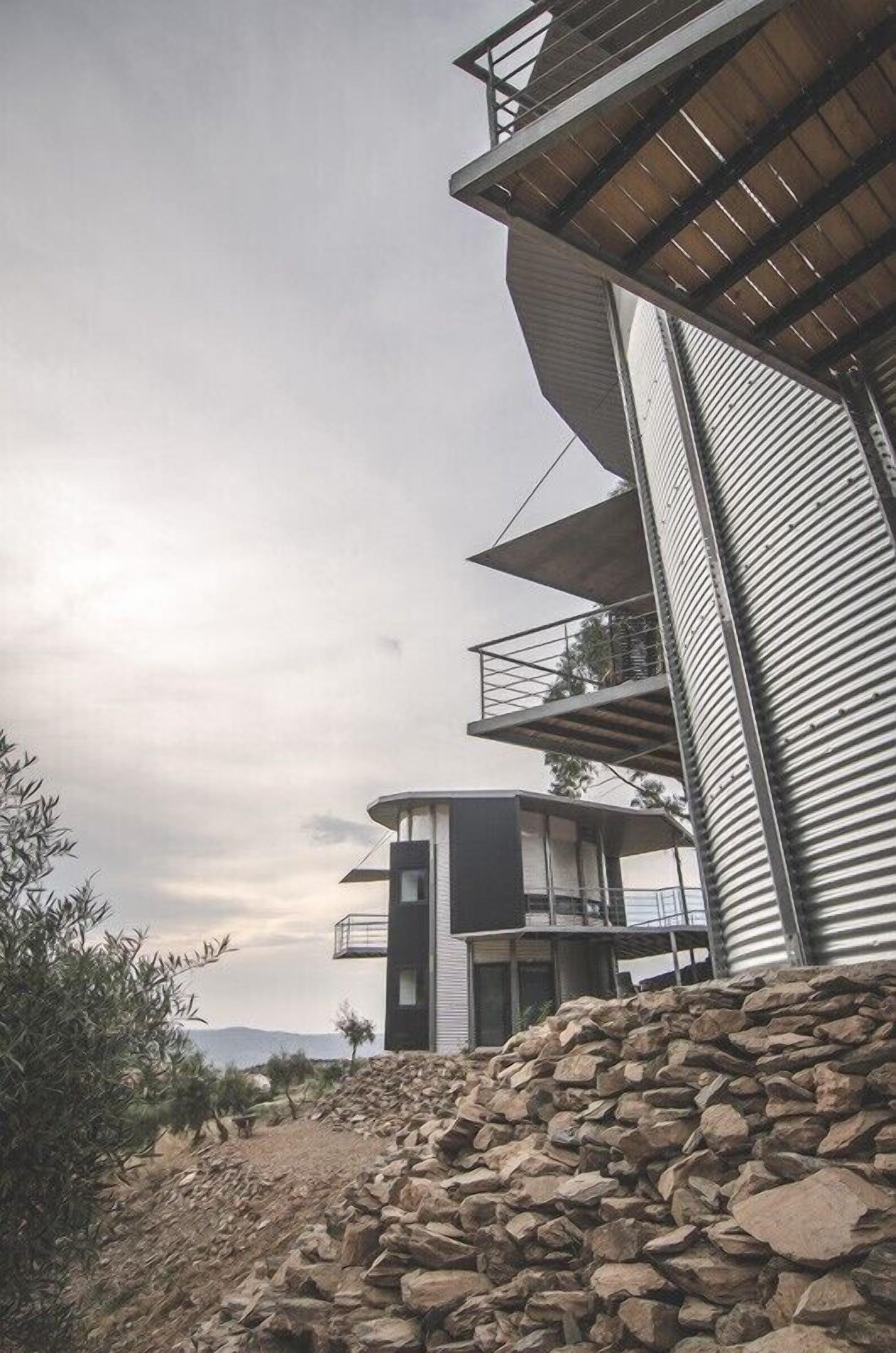 Um edifício moderno com várias varandas e um muro de pedra em primeiro plano.