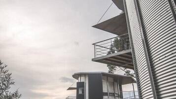 Um edifício moderno com várias varandas e um muro de pedra em primeiro plano.