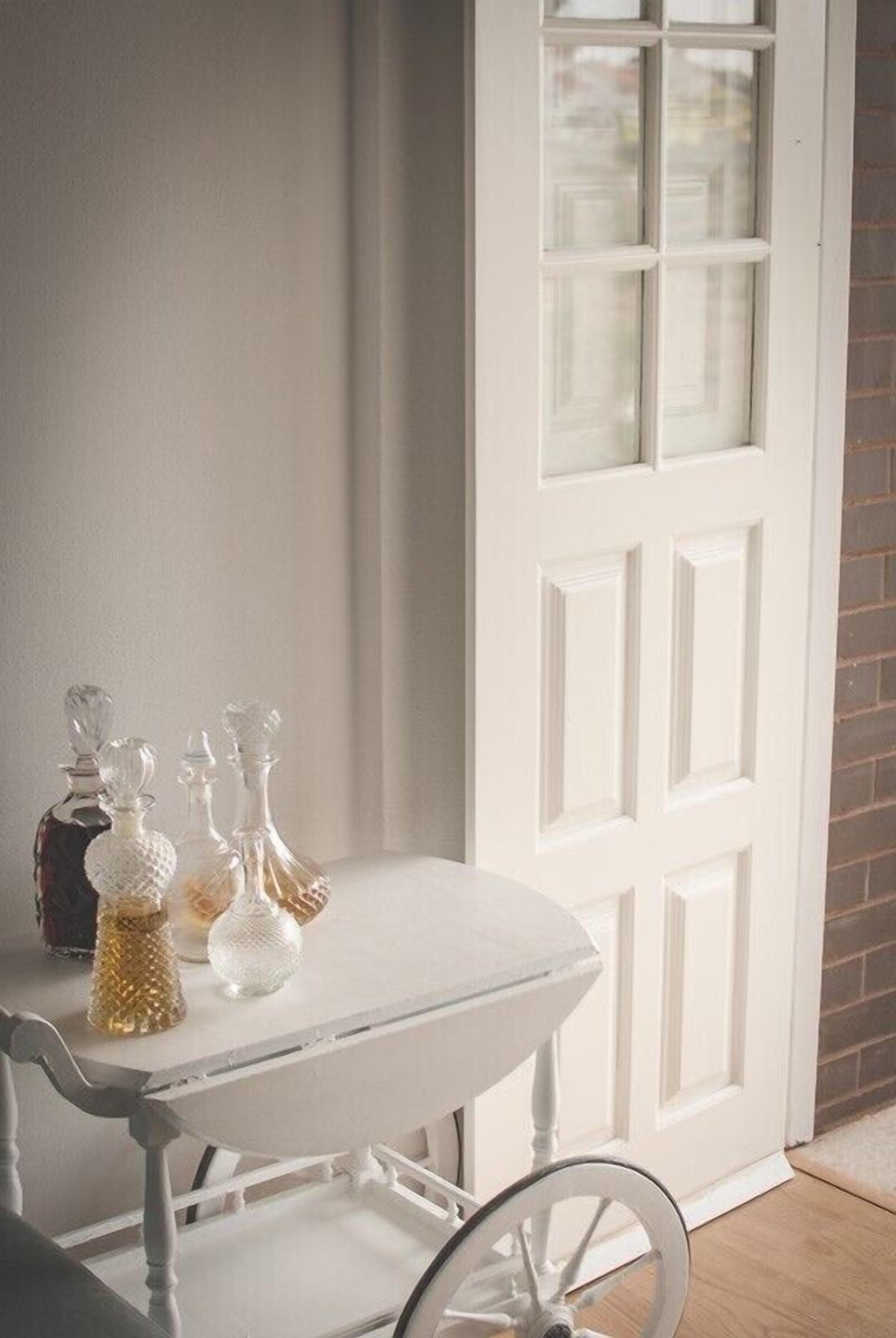 Une table blanche avec des carafes en verre et une chaise blanche à ossature métallique.