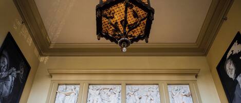 Teto com um candeeiro decorativo e três painéis de parede iluminados com relevos escultóricos clássicos.