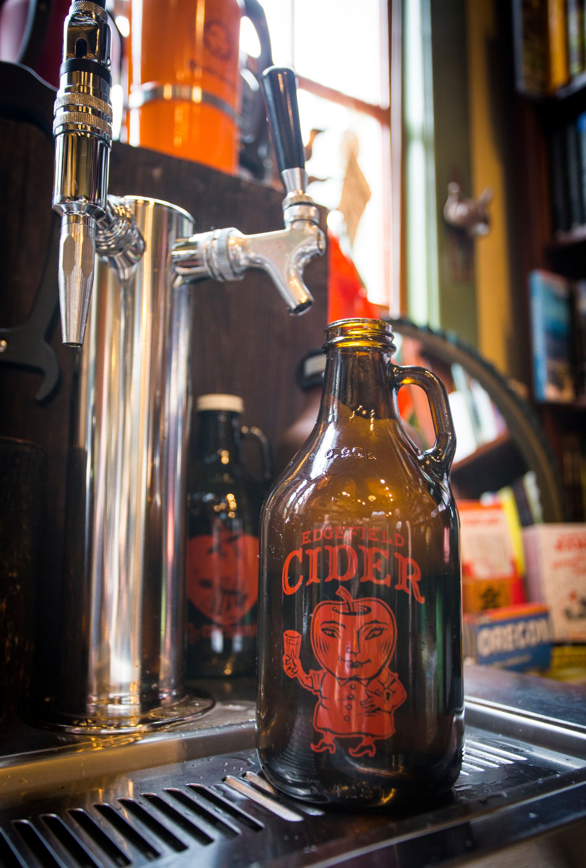 A copper tap and a glass jug with a label on a bar counter.