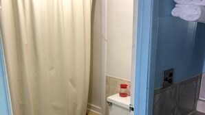 A bathroom with a shower curtain, a toilet, and a sink with a towel rack. - Friendly Inn Motel (Harrisburg)
