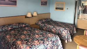 A room with two beds, a wooden headboard, two wall-mounted lamps, and a small round table. - Friendly Inn Motel (Harrisburg)