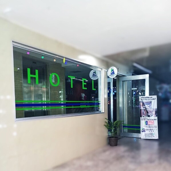 A hotel entrance with a glass door, a sign reading "HOTEL," and a small potted plant beside it. - Granda Inn (Tuxtla Gutierrez)