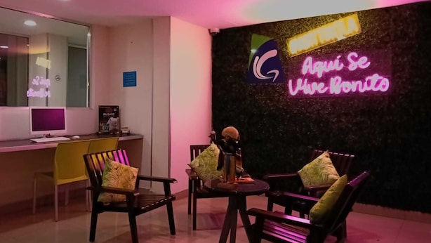 A reception area with a desk, chairs, and a neon sign. - Granda Inn (Tuxtla Gutierrez)