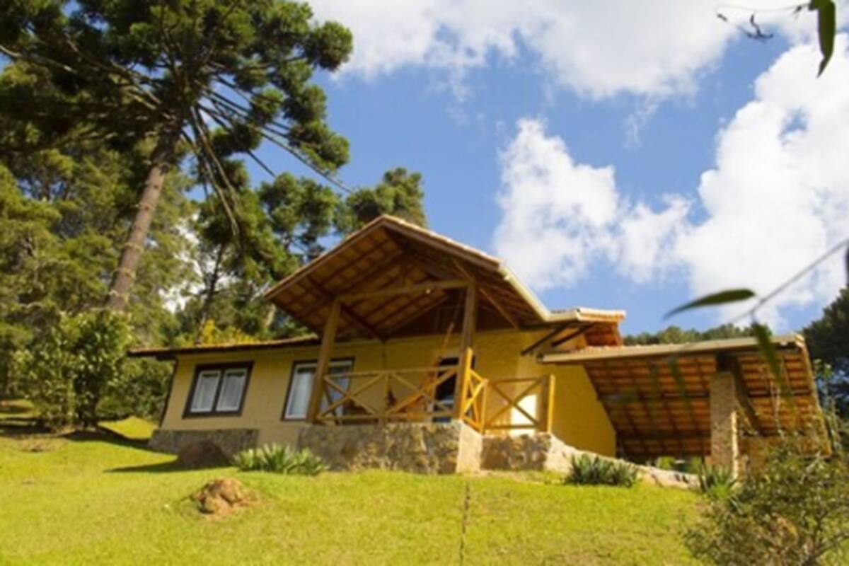 Una casa de un piso con techo inclinado, porche de madera y cimientos de piedra.