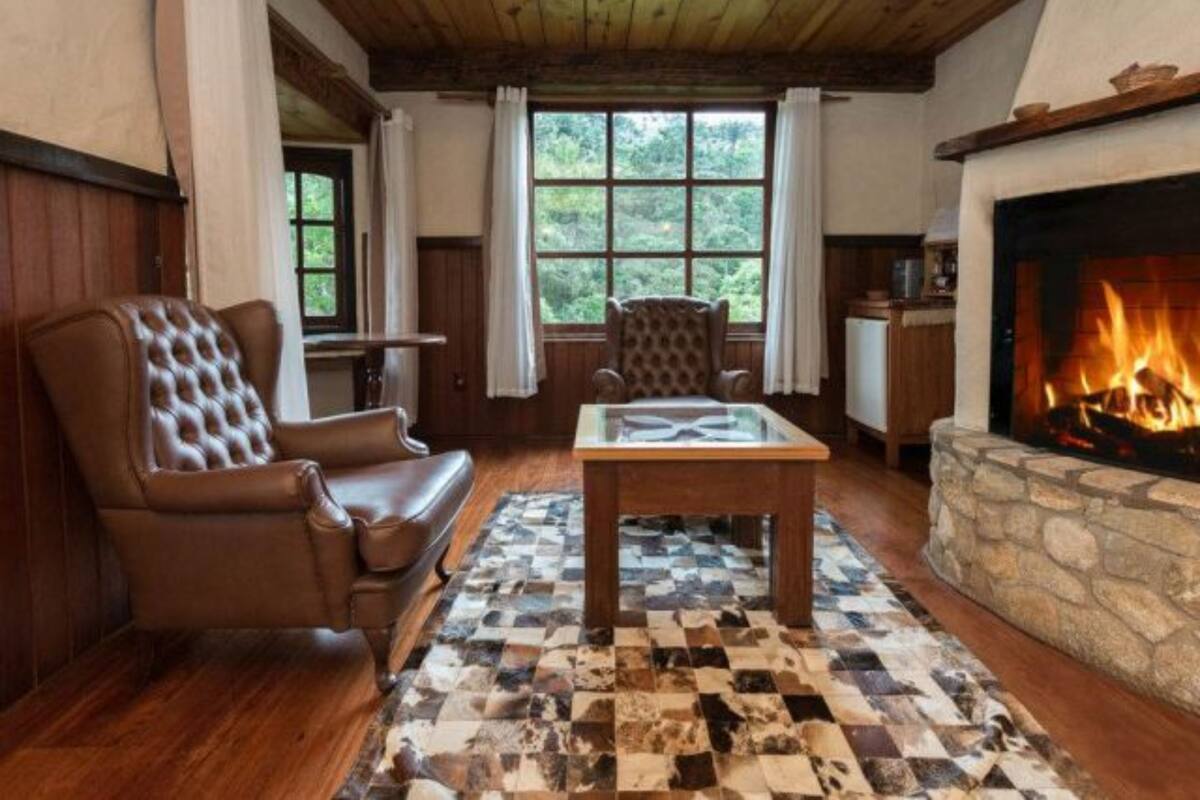 Una sala de estar acogedora con chimenea, sillón de cuero y alfombra a cuadros.