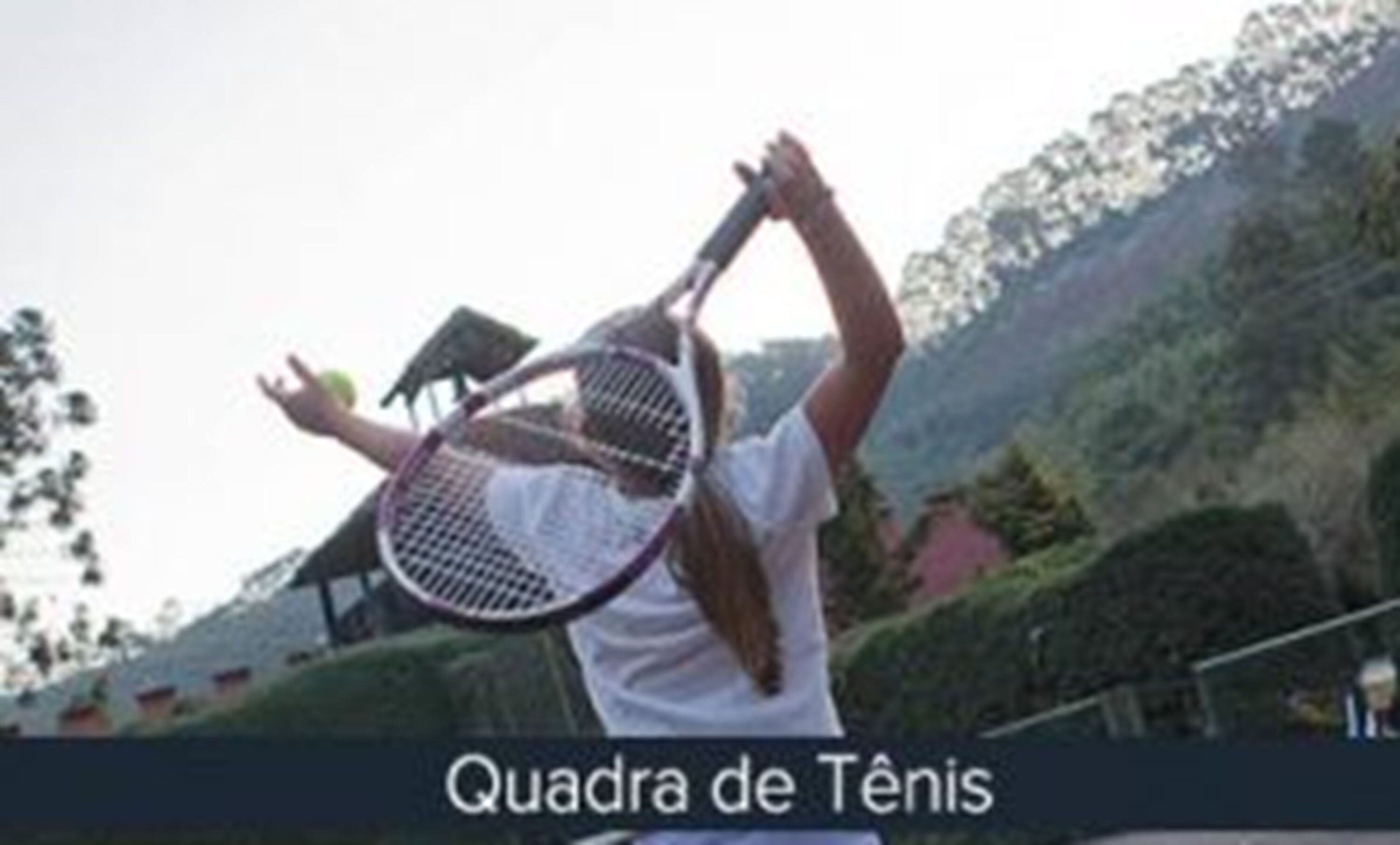 Uma quadra de tênis com uma rede e uma pessoa segurando uma raquete.