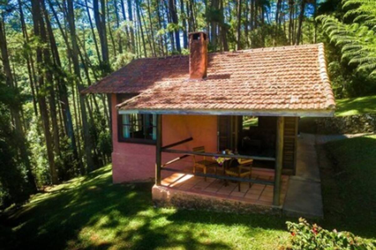 Una casa pequeña de un solo piso con tejado de baldosas, una chimenea y un balcón con sillas.