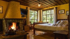 Une pièce chaleureuse avec une cheminée en pierre, un lit et de grandes fenêtres.