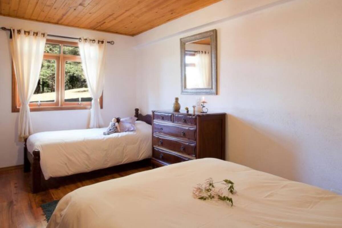 Un dormitorio con dos camas, un aparador, un espejo y una ventana con cortinas.