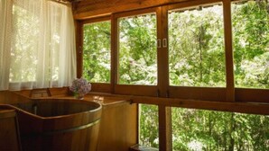 L’intérieur d’un chalet en bois, avec de grandes fenêtres, une baignoire en bois et un luminaire suspendu.