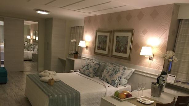 Une chambre d’hôtel comprenant un lit, une table de chevet, une lampe, un tableau encadré et un bureau avec une chaise.
