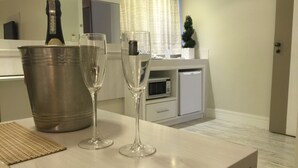 Une cuisine moderne avec un grand seau en métal, deux verres à vin, un four à micro-ondes et un petit réfrigérateur.