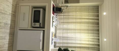 A compact kitchen with a microwave, refrigerator, and a small sink.
