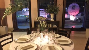 Une table à manger dressée pour six personnes, avec une nappe blanche, des assiettes et des couverts.