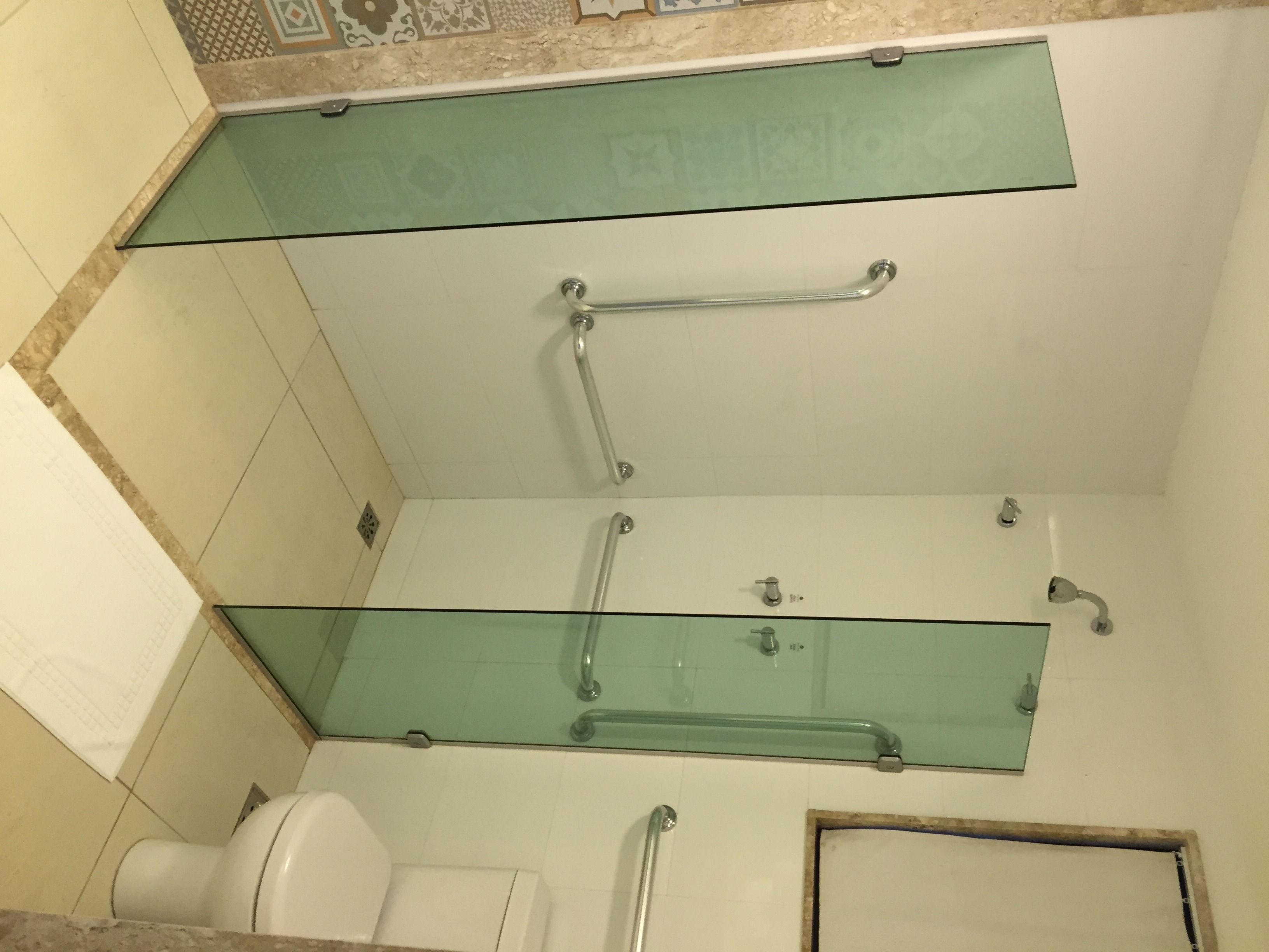 Un baño con cabina de ducha de vidrio, inodoro y lavamanos.