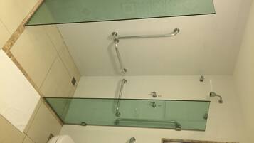 Un baño con cabina de ducha de vidrio, inodoro y lavamanos.