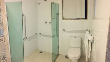 A bathroom with a glass-enclosed shower, a toilet, and a handrail.