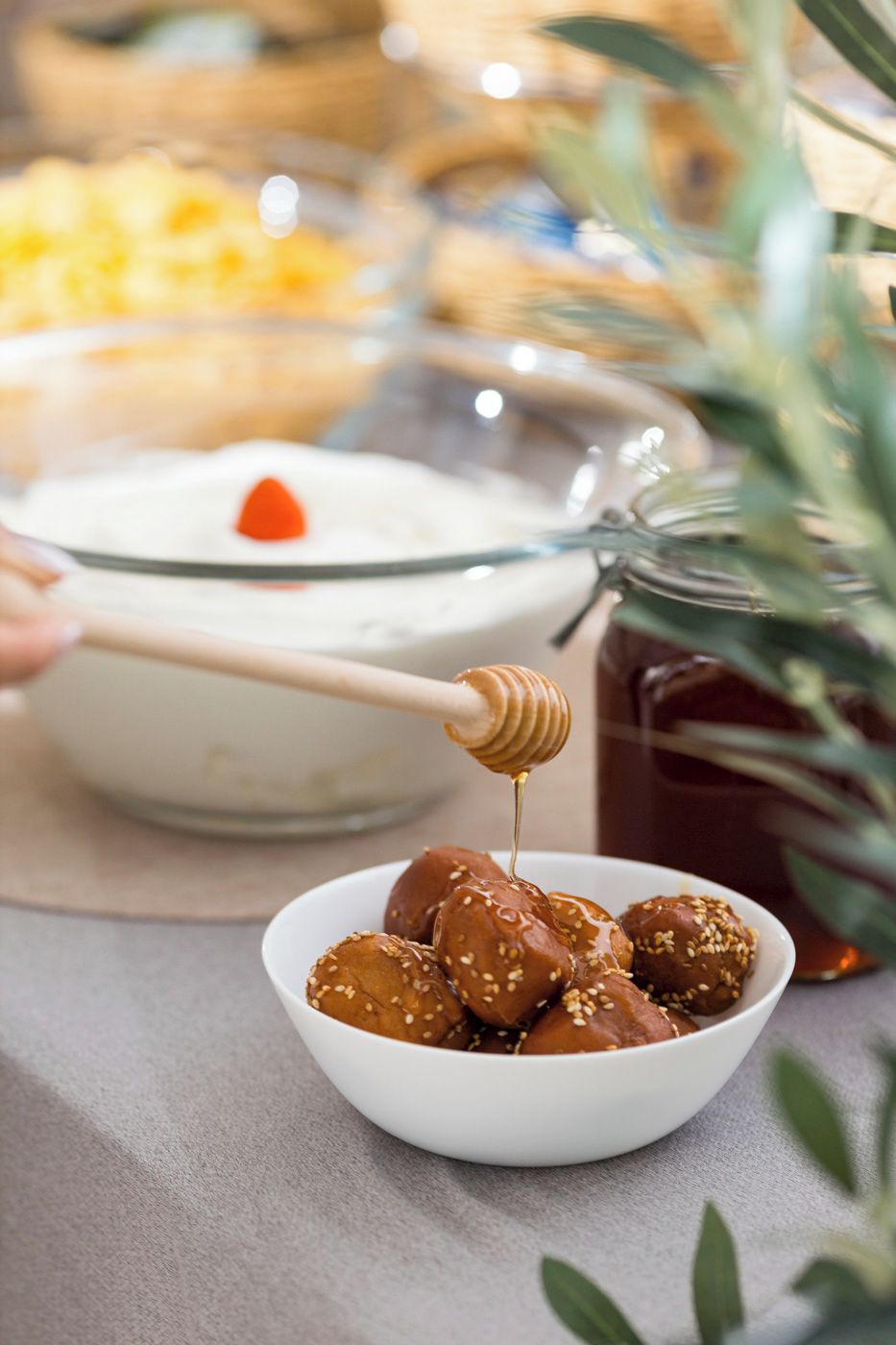 A bowl of sesame-seed coated items with honey being drizzled on them.