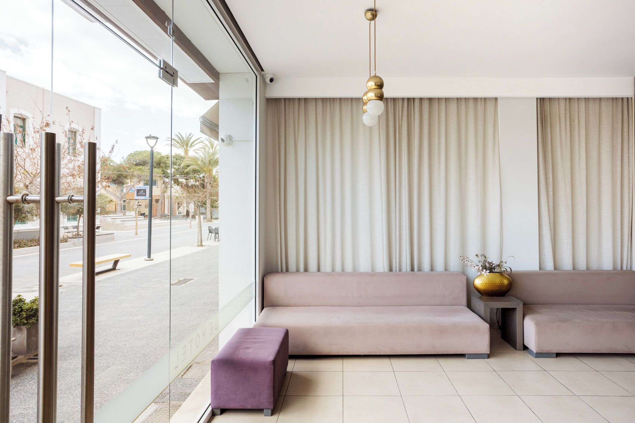 A modern living room with a sofa, ottoman, and a decorative vase.