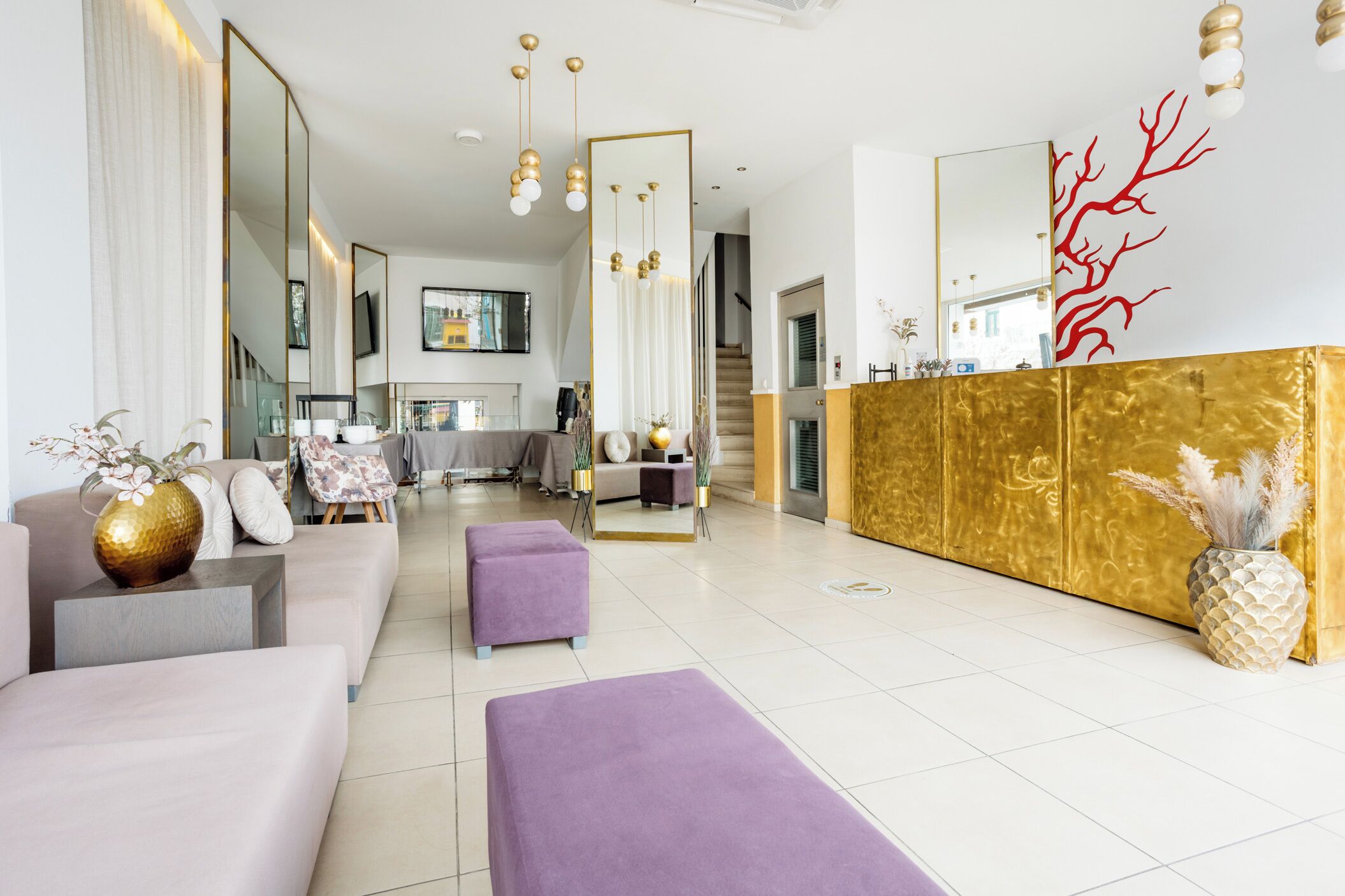 Un salon moderne avec un canapé, un pouf et un comptoir d’accueil doré.