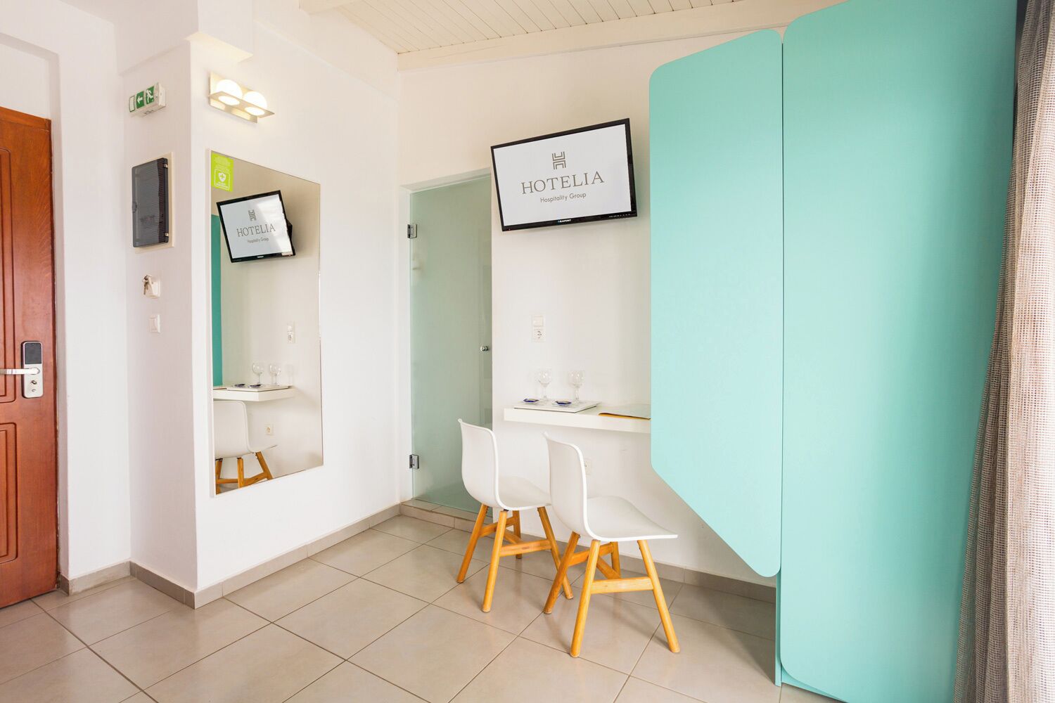 Habitación de hotel con un escritorio blanco, una silla, un espejo y un cartel enmarcado en la pared.
