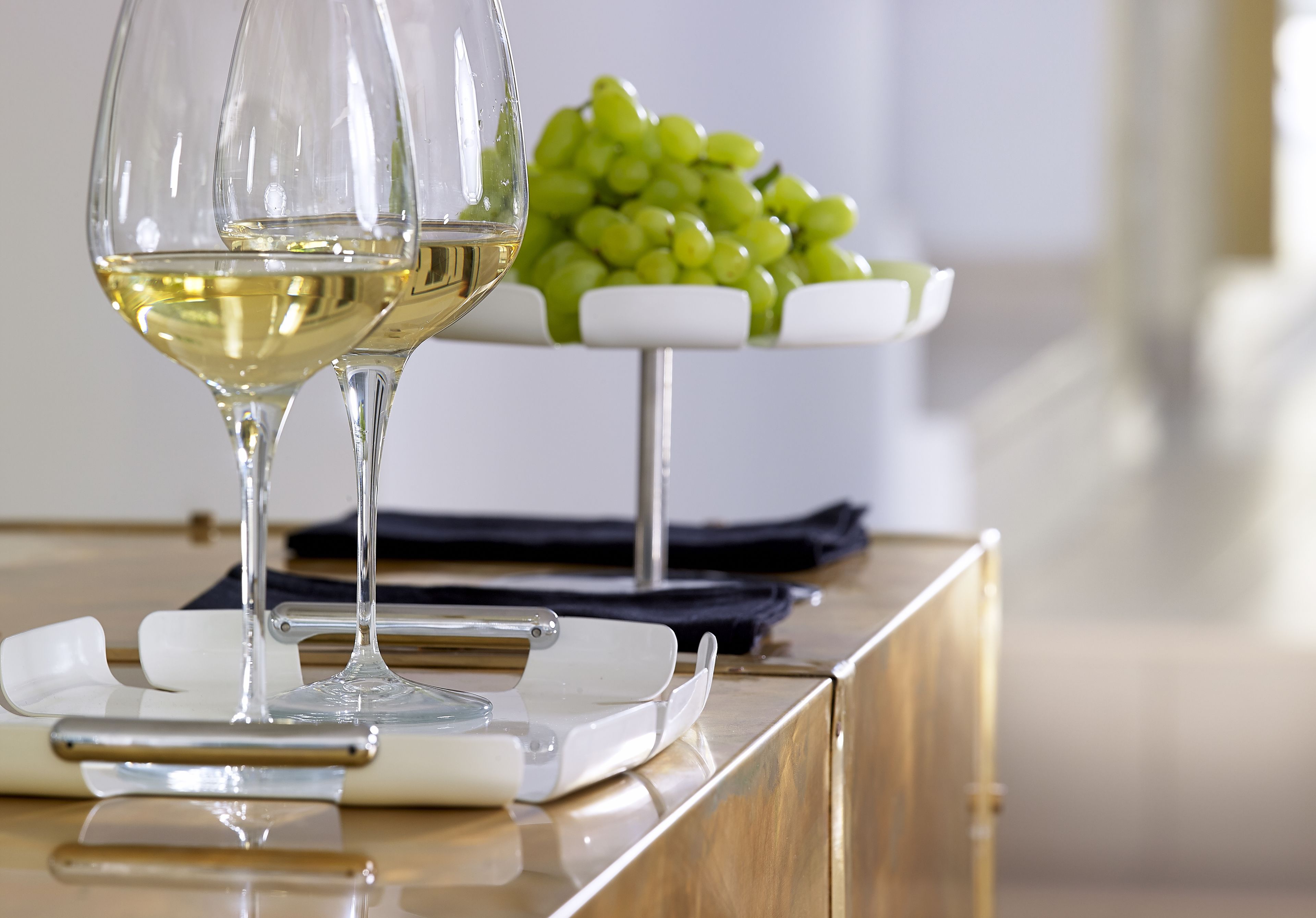 A table with two wine glasses and a bowl of green grapes.