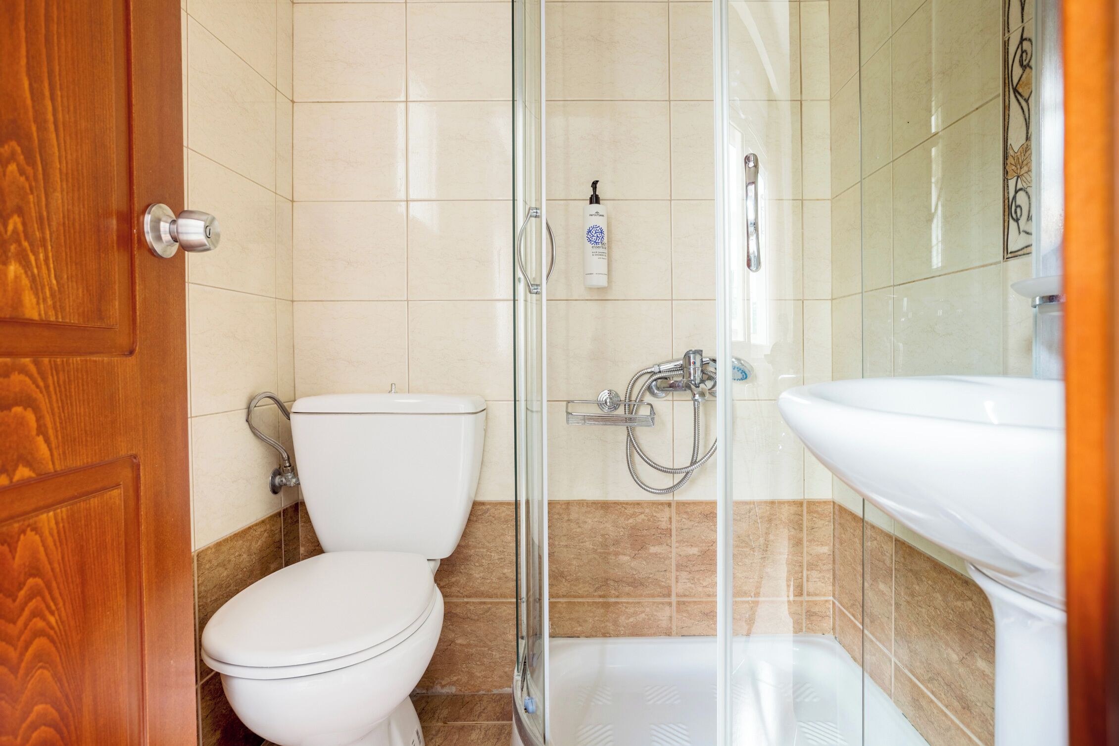 A bathroom with a toilet, shower, and sink.