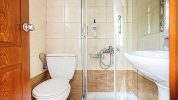 A bathroom with a toilet, shower, and sink.