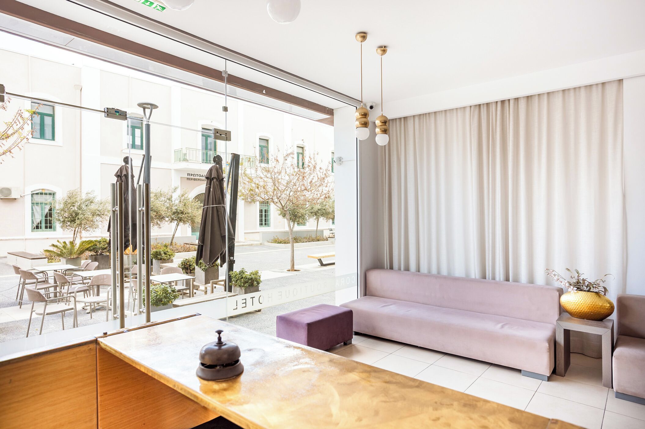 A modern hotel room with a large window, a sofa, a small table, and a decorative vase.