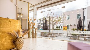 Vestíbulo de hotel con mostrador de recepción, un espejo grande y vista a la calle.