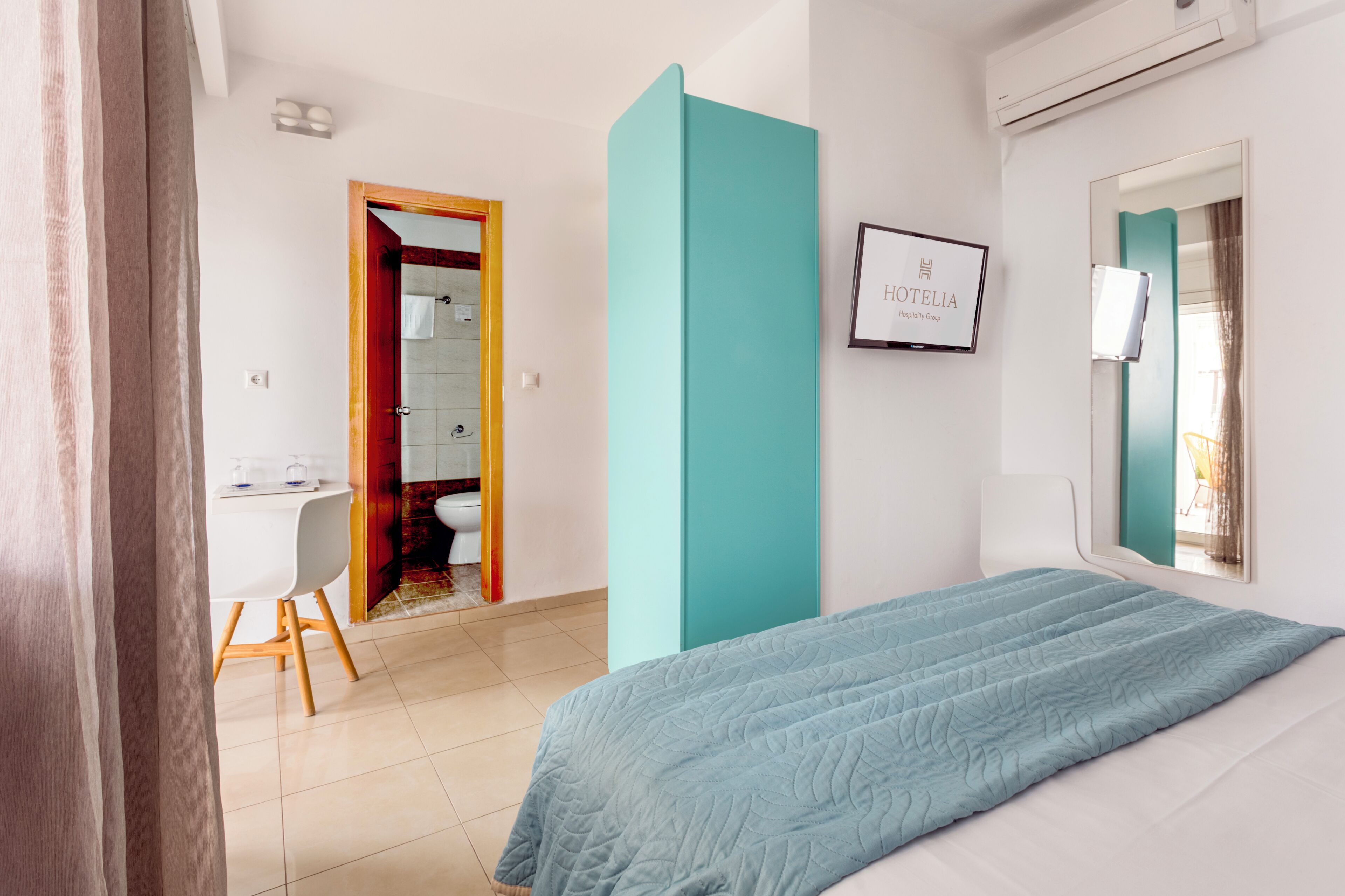 Habitación de hotel con cama, escritorio, silla, baño y un cartel enmarcado en la pared.