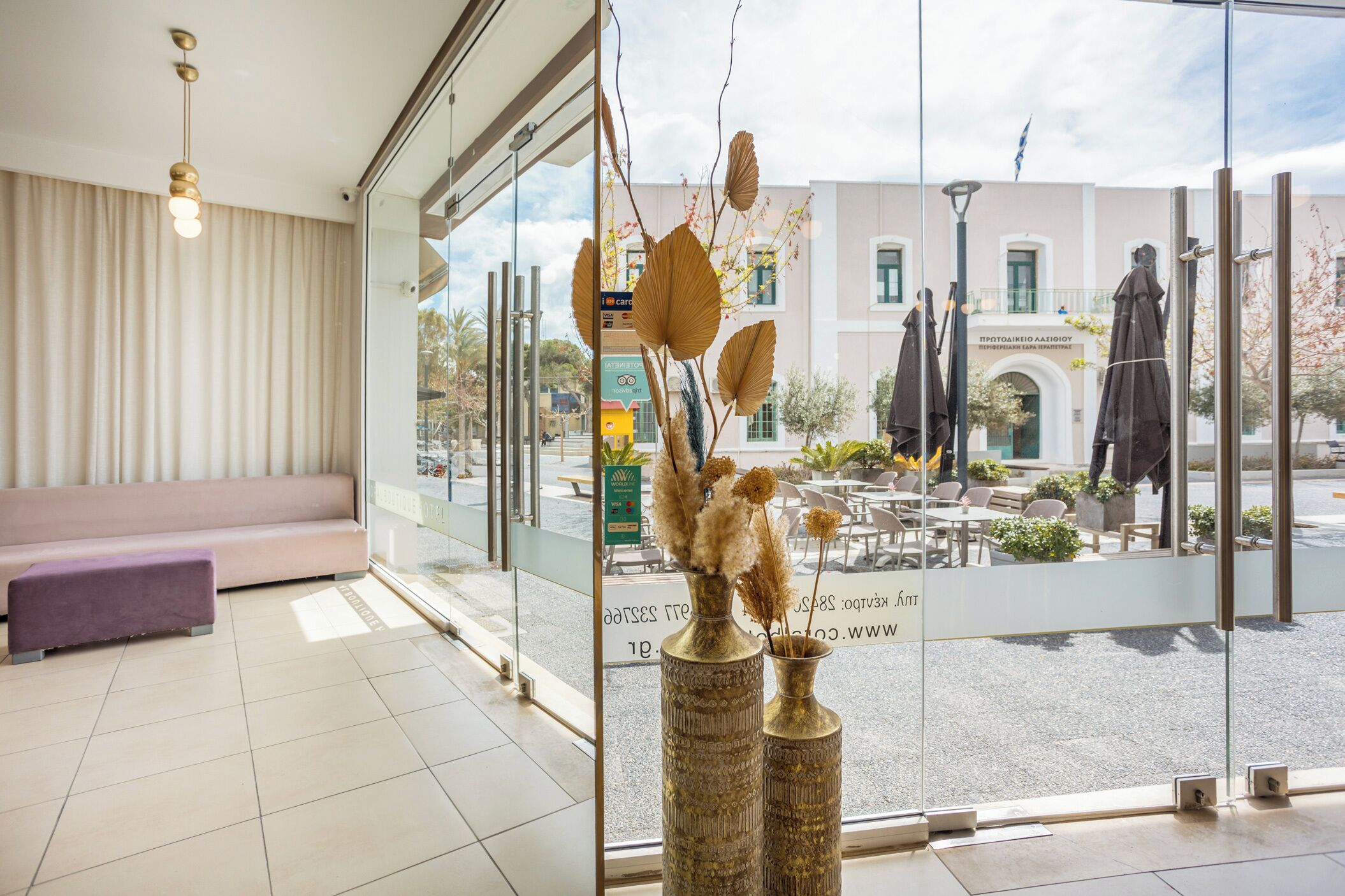 A modern hotel lobby with a seating area, large windows, and decorative vases.