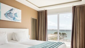 Camera d'albergo con un ampio letto, vista sull'oceano e un quadro appeso al muro.