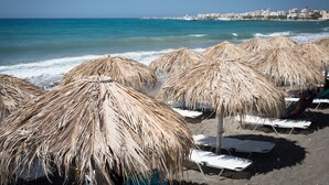Una spiaggia con ombrelloni di paglia e lettini.