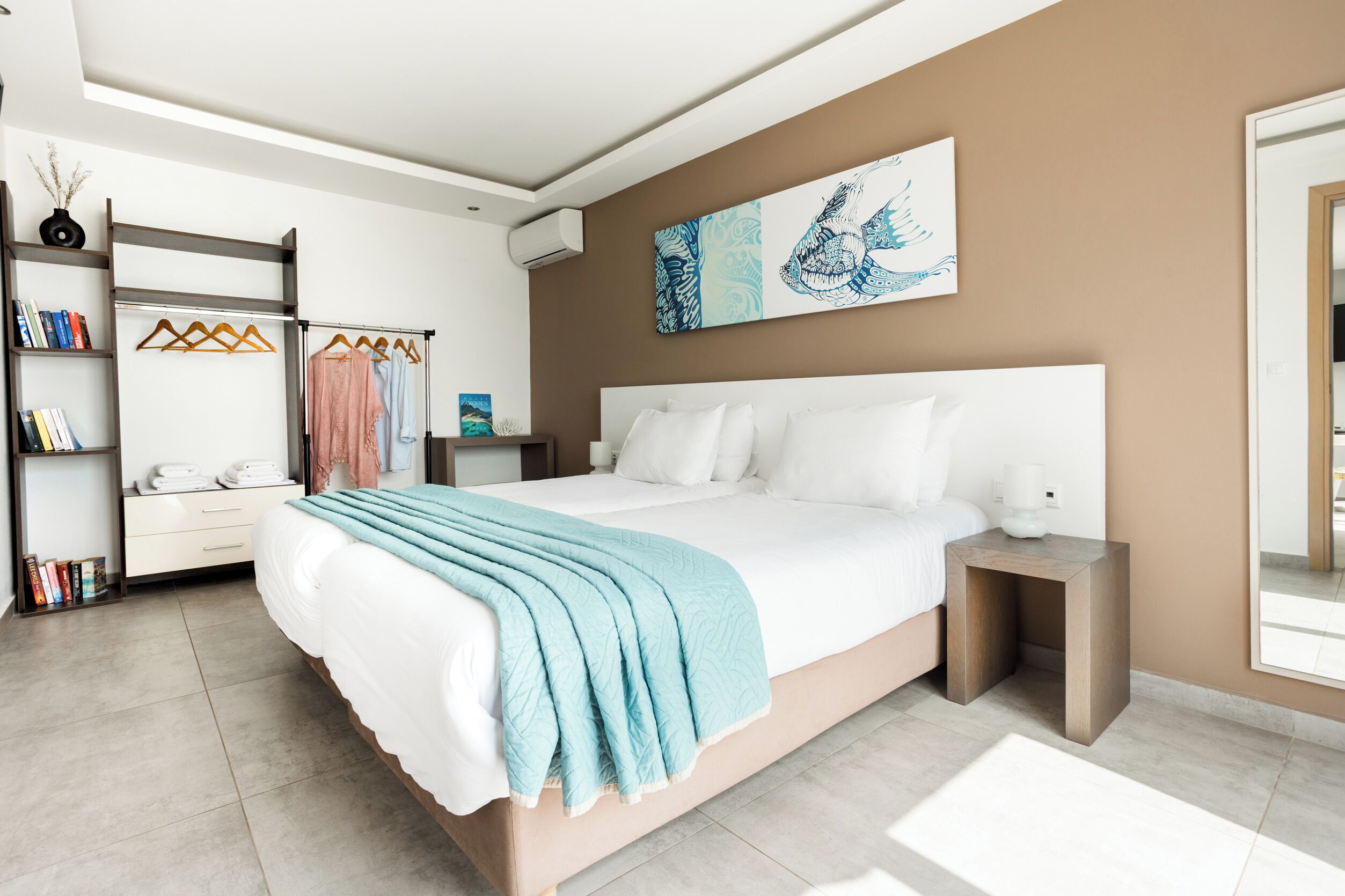 A modern bedroom with a large bed, a wardrobe, a bedside table, and a wall-mounted artwork.