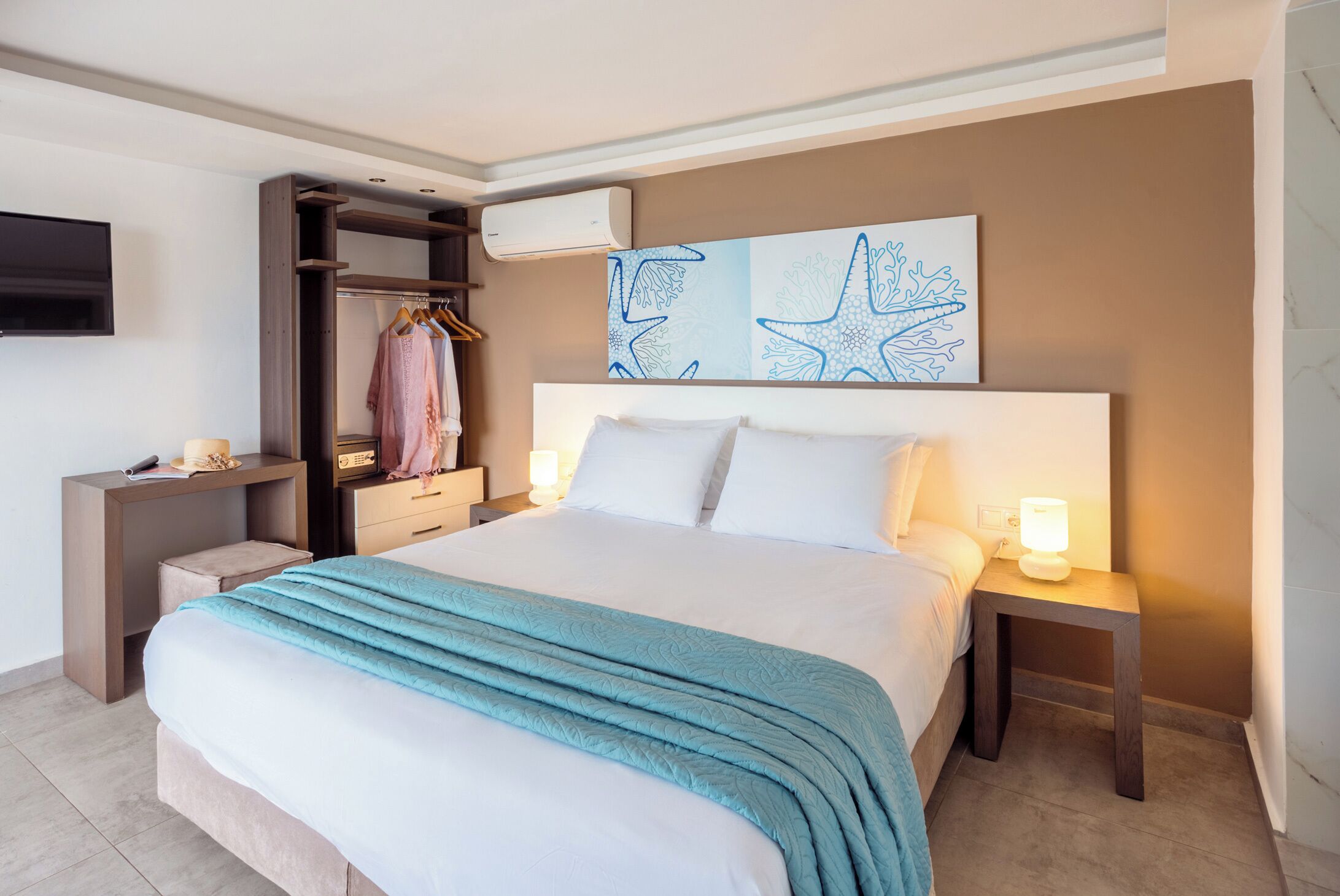 Hotelkamer met een bed, nachtkastjes, een kledingkast, een flatscreen-tv en kunst aan de muur.