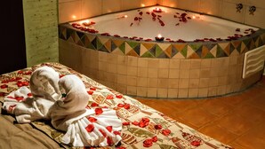 Un cuarto de spa con una bañera rodeada de pétalos de rosa, una toalla y un tapete de baño.