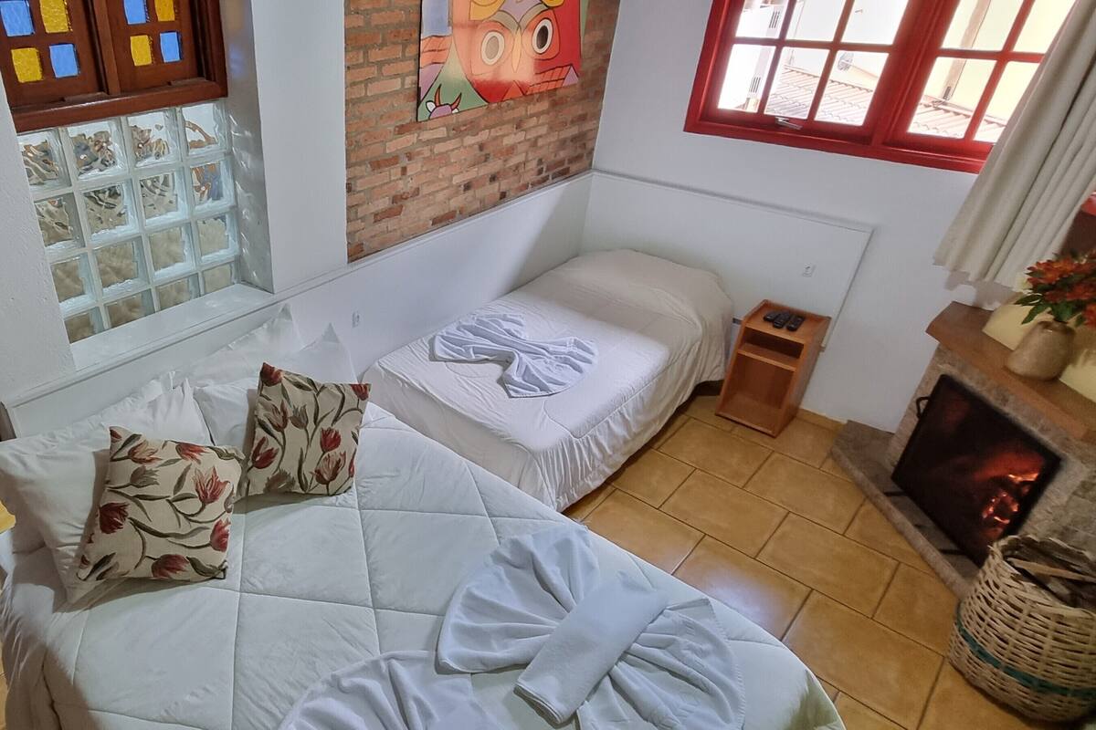 A bedroom with two beds, a fireplace, and a window with a view.