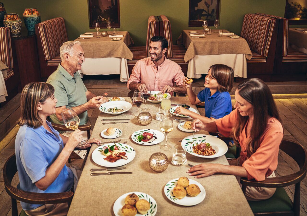 A dining room with a long table set for a meal, surrounded by chairs.