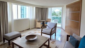 A spacious living area with a large window, a dining table, and comfortable seating. - Grand Park Royal Cozumel - All Inclusive (Cozumel)