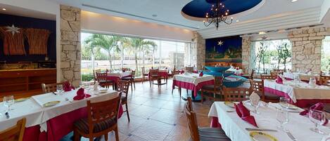Un restaurant doté de nombreuses tables, de chaises et d’une grande fenêtre offrant une vue sur les palmiers.