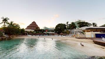 A resort with a pool, beach chairs, and a pyramid-shaped building.
