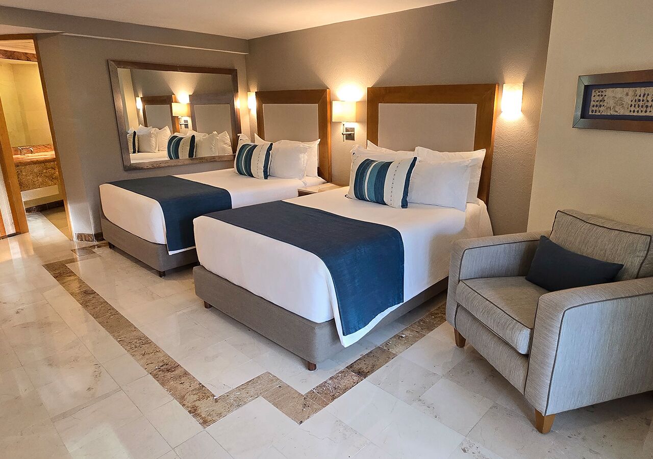 Une chambre d’hôtel avec deux lits, un canapé et un grand miroir.