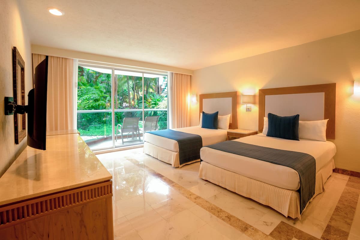 Habitación de hotel con dos camas, televisión, escritorio y ventana grande con vistas a zonas verdes.