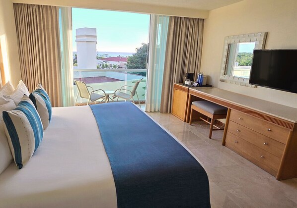 Una habitación de hotel con una cama grande, un escritorio, una silla, un televisor y vistas al exterior.