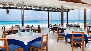 A seaside restaurant with tables set for dining, overlooking the ocean. - Grand Park Royal Cozumel - All Inclusive (Cozumel)