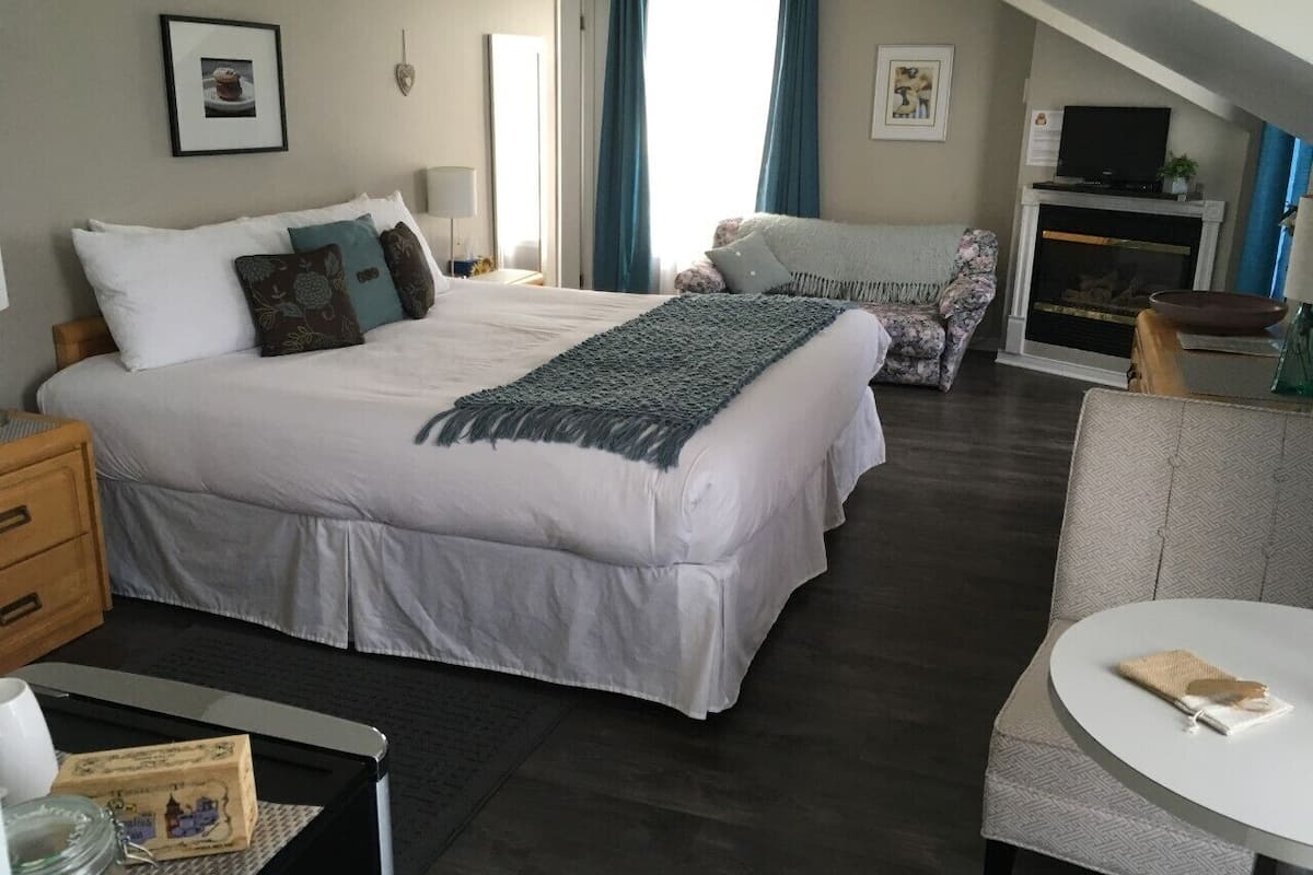 Una habitación de hotel con una cama grande, un sofá, una mesa de comedor y una chimenea.