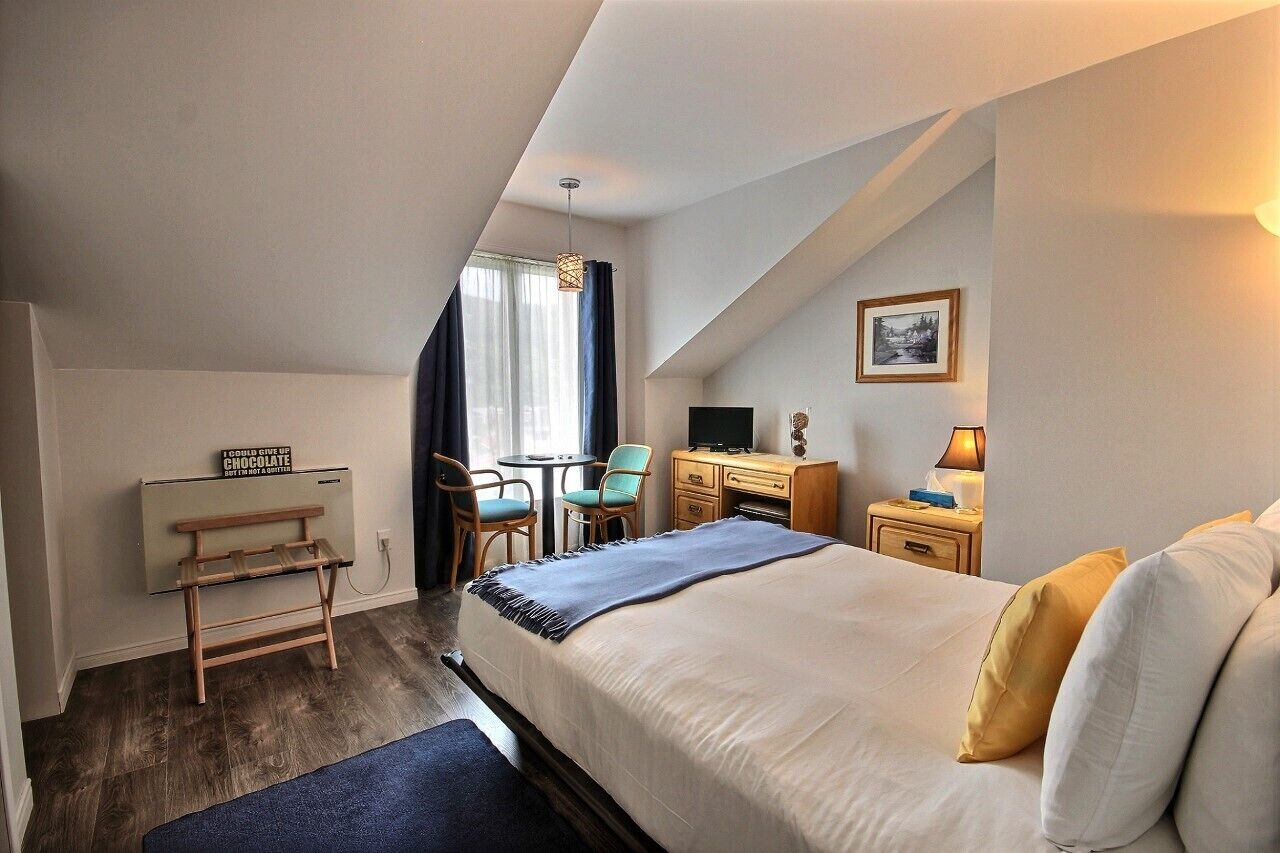 A hotel room with a bed, desk, chair, and a small table.